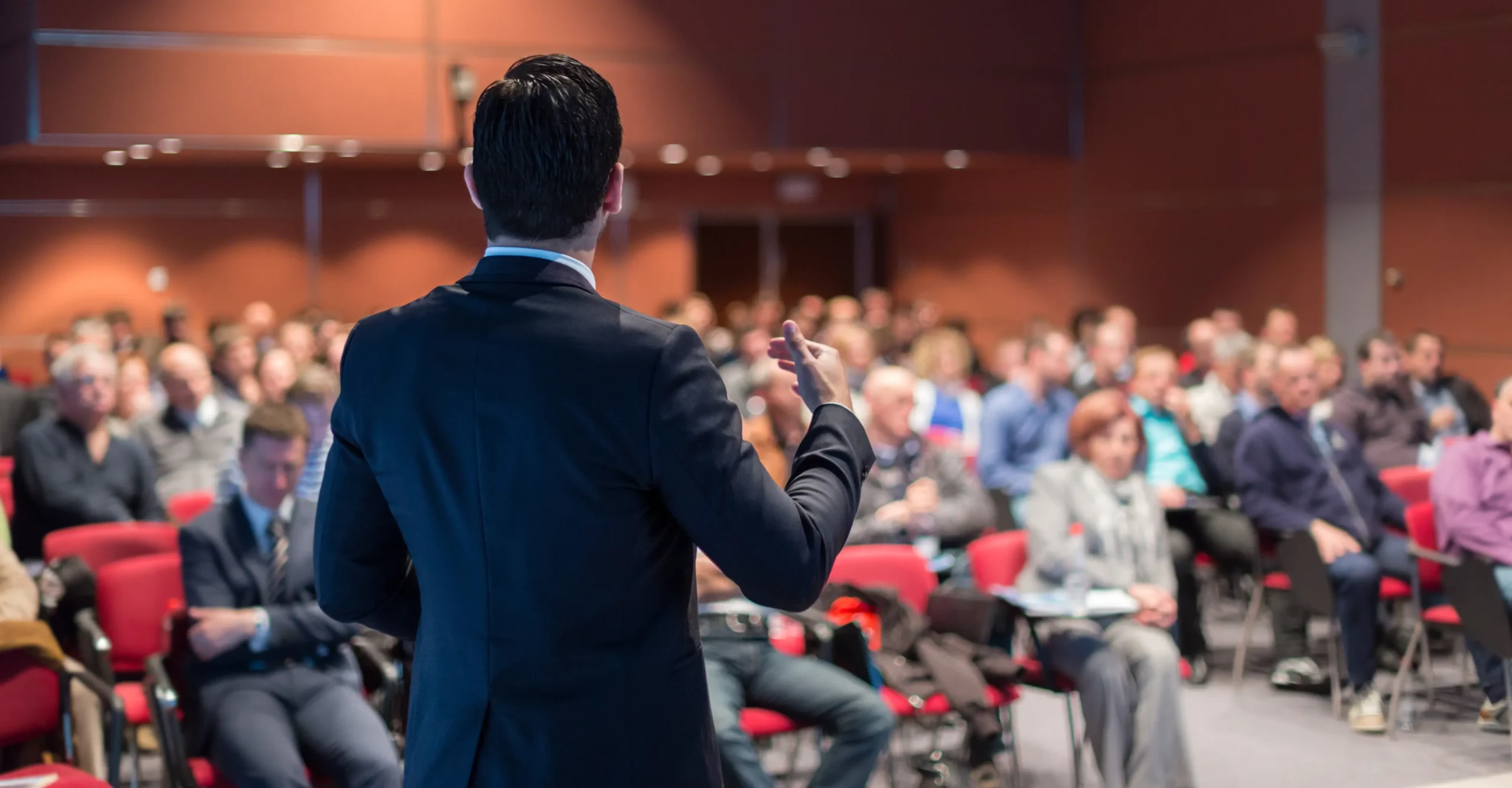 Speaker presenting at a seminar to a large audience